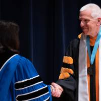 President and Faculty member shaking hands on stage